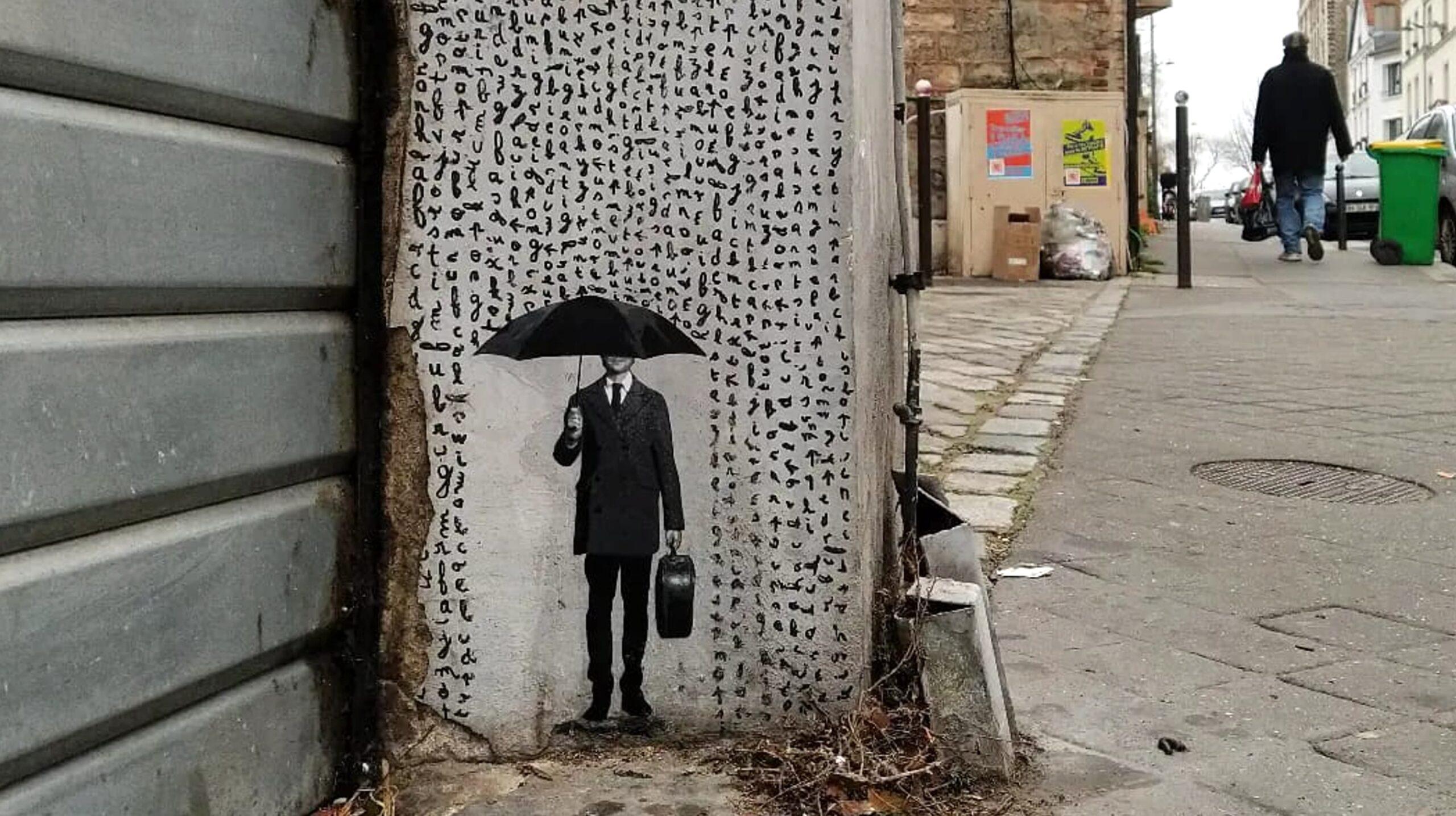 Oeuvre au pochoir réalisée au pied d'un mur à Paris. L'oeuvre représente un homme en costume se protégeant avec un parapluie du pluie de lettres. L'oeuvre a été réalisée par le street artiste parisien Ender.