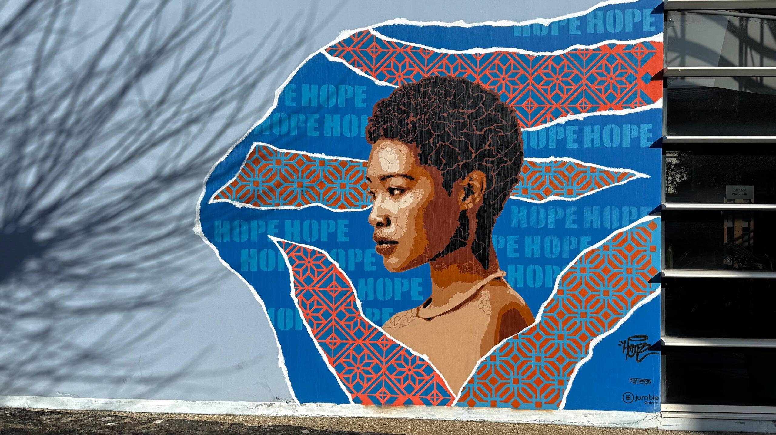 Oeuvre murale représentant le portrait de profil d'une femme d'origine africaine sur un fond avec le mot hop écrit de multiples fois.