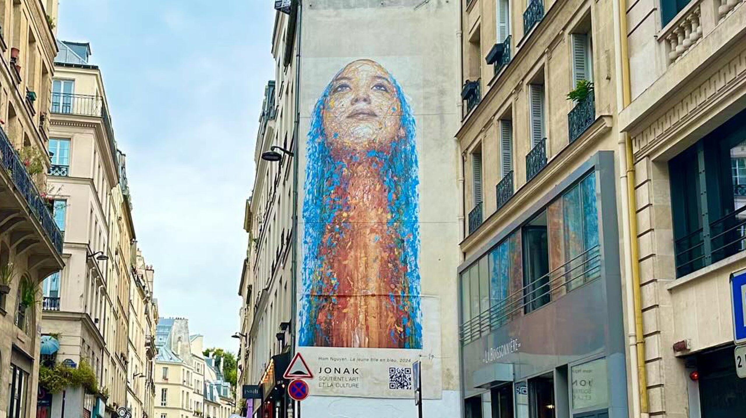Grand portrait d'une jeune fille regardant le ciel réalisé sur un mur de Paris par l'artiste Hom Nguyen.